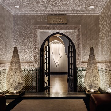 A spa entrance with a sign, a chandelier, and decorative lamps.