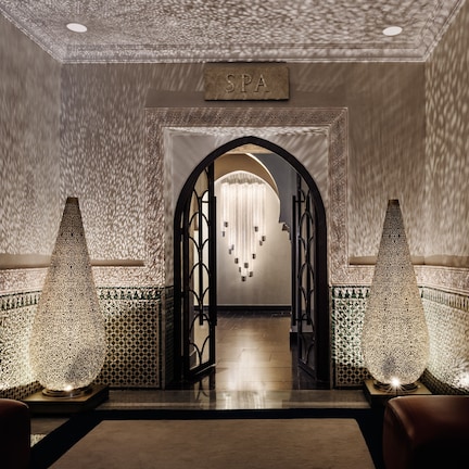 A spa entrance with a sign, a chandelier, and decorative lamps.