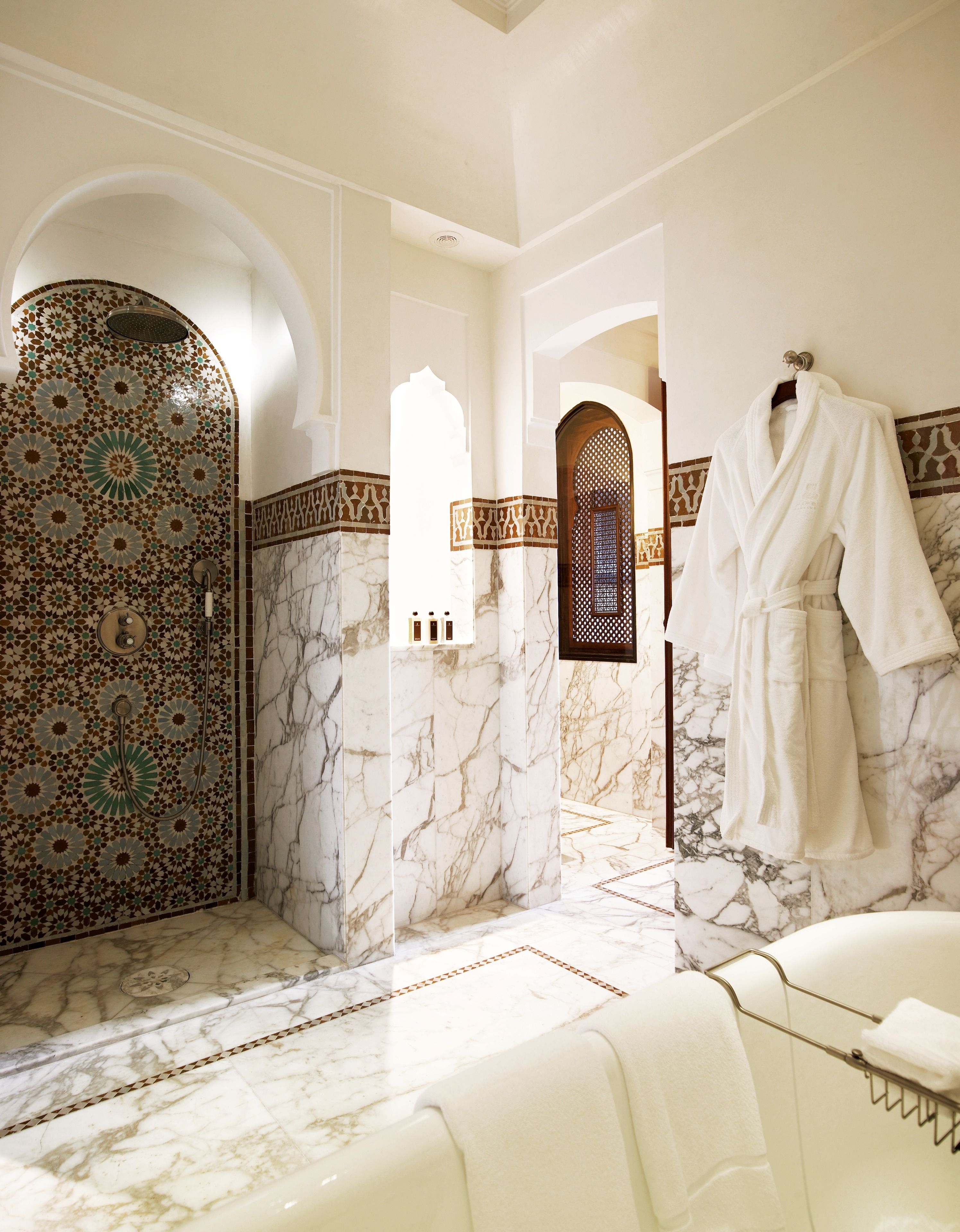 A luxurious bathroom with a marble floor, a bathtub, and a shower with intricate tile work.