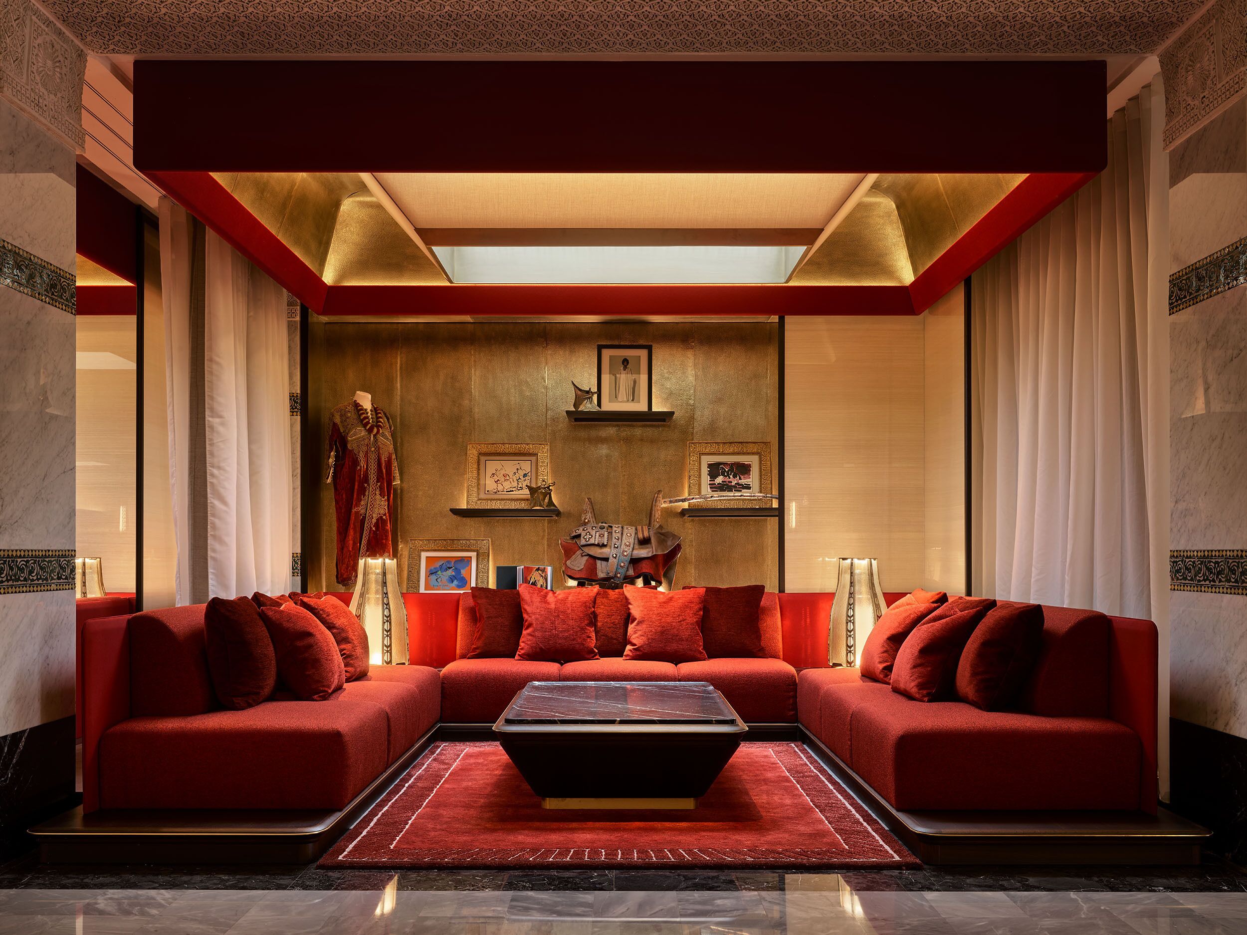 Ein luxuriöses Wohnzimmer mit einem roten Ecksofa, einem Couchtisch und einem Kronleuchter.