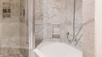 Une salle de bain avec un sol en marbre, une baignoire, un espace douche et une cabine de douche en verre.