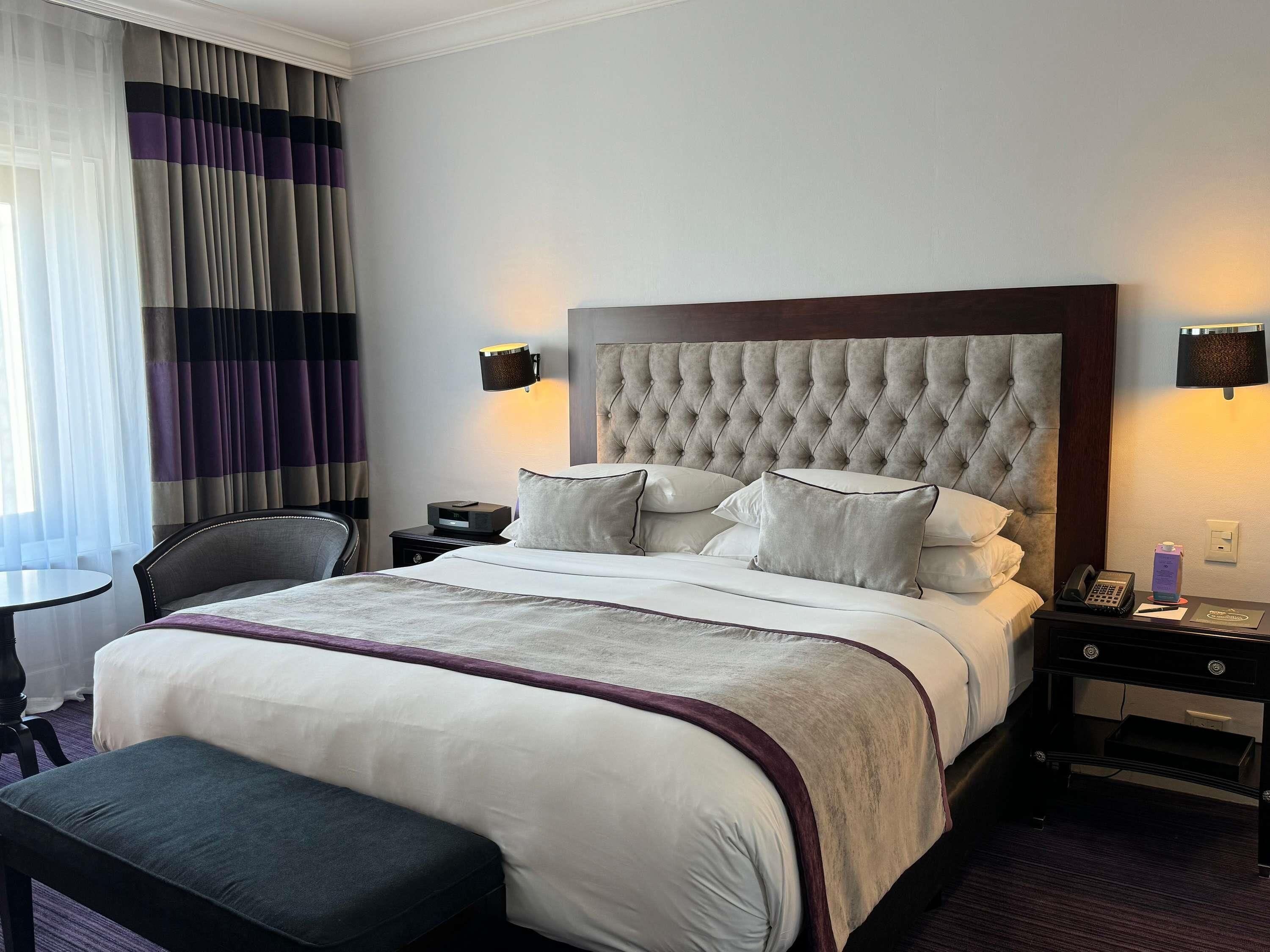 Una habitación de hotel con una cama grande, una mesita de noche, una silla y un escritorio.