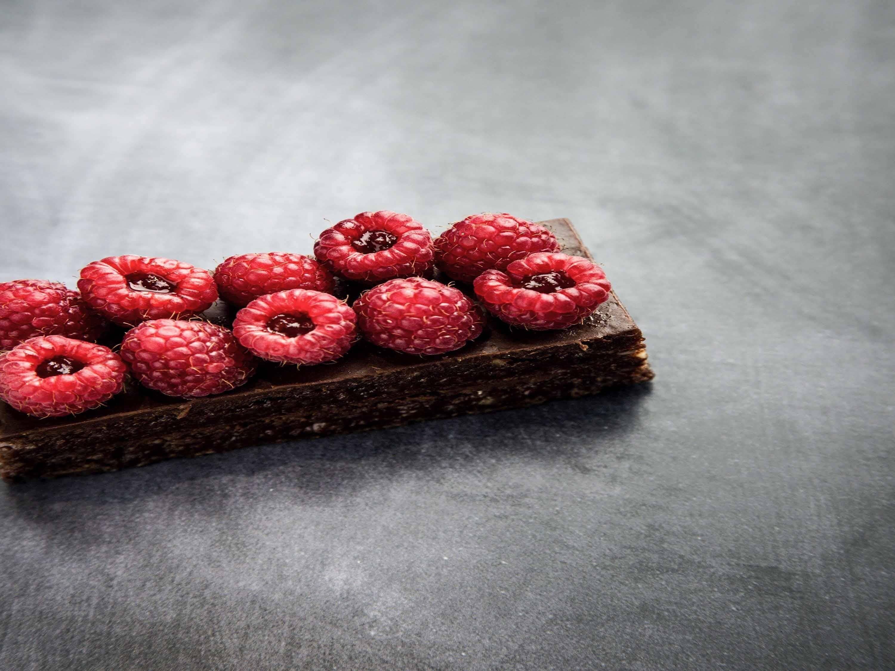 Una pila de barras de chocolate cubiertas de frambuesas.