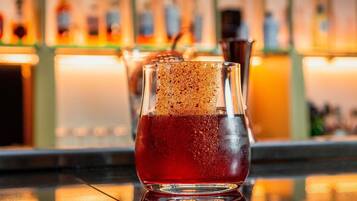 A bar setting with a glass containing a dark beverage, a frothy top, and a straw.