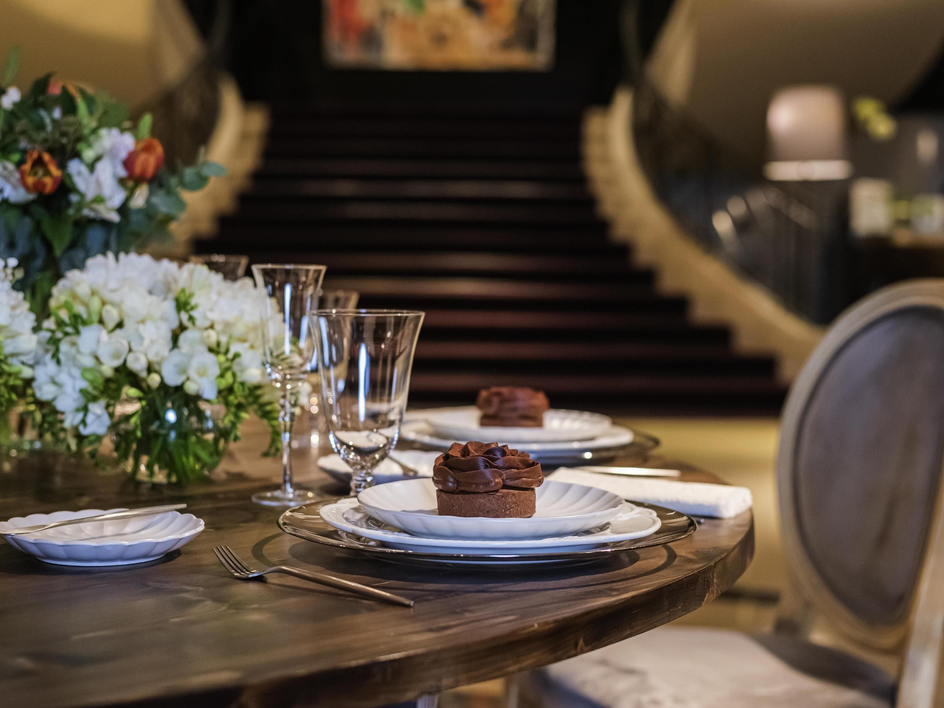 A dining table with plates, glasses, and a dessert.