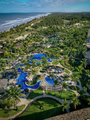 Um resort com várias piscinas, palmeiras e vista para o oceano.