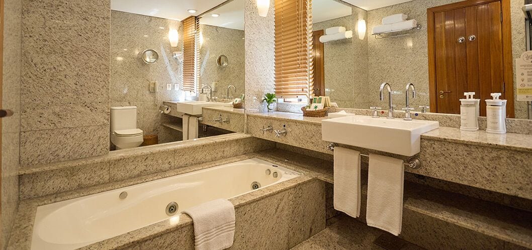 Een moderne badkamer met een groot bad, twee wastafels en een spiegel.