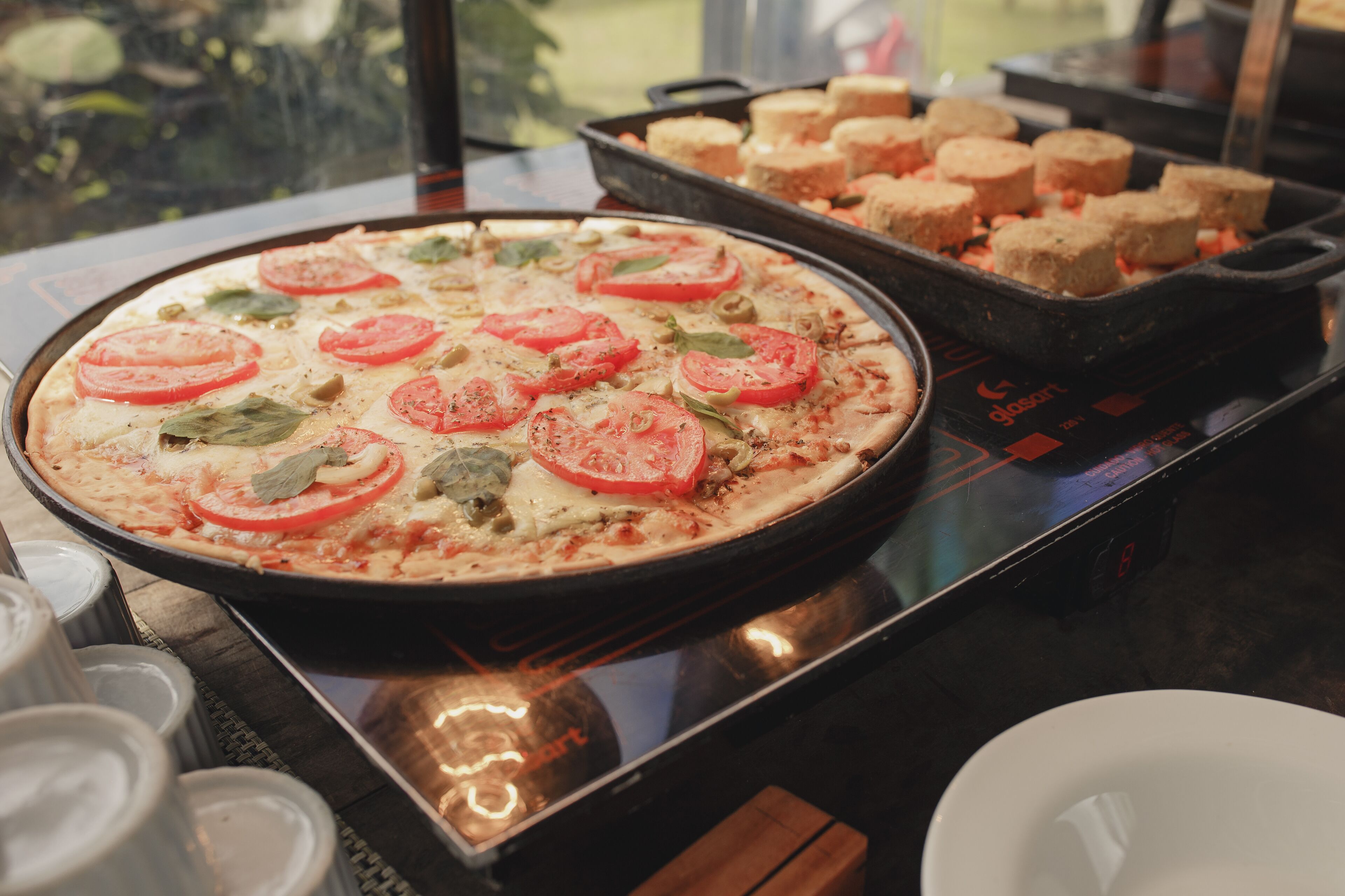 Una pizza con rodajas de tomate y albahaca en una bandeja.