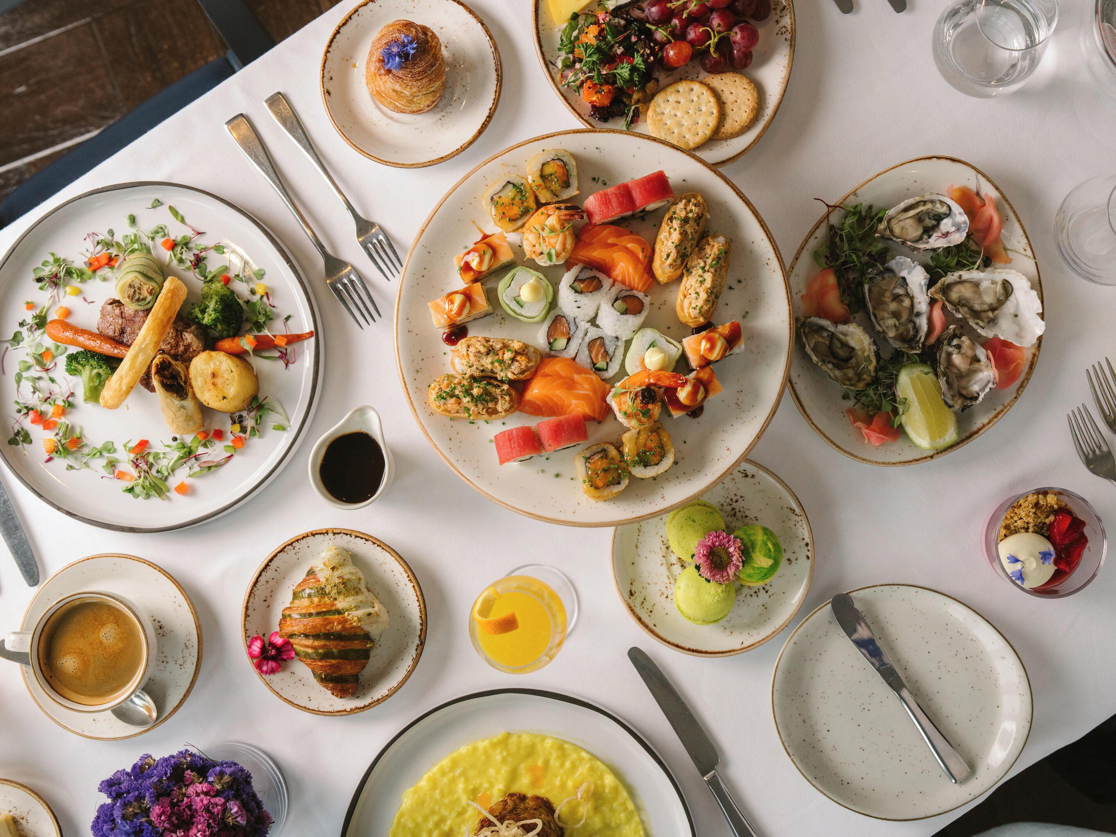 A table with various dishes, utensils, and a glass of orange juice.