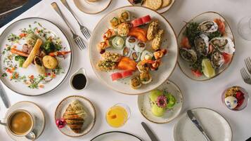 A table with various dishes, utensils, and a glass of orange juice.