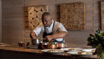 Un chef cocina en una cocina con detalles de madera en las paredes y una planta en la encimera.