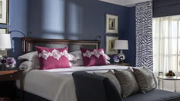 Una habitación de hotel con una cama grande, una mesita de noche, una lámpara y una ventana con cortinas.