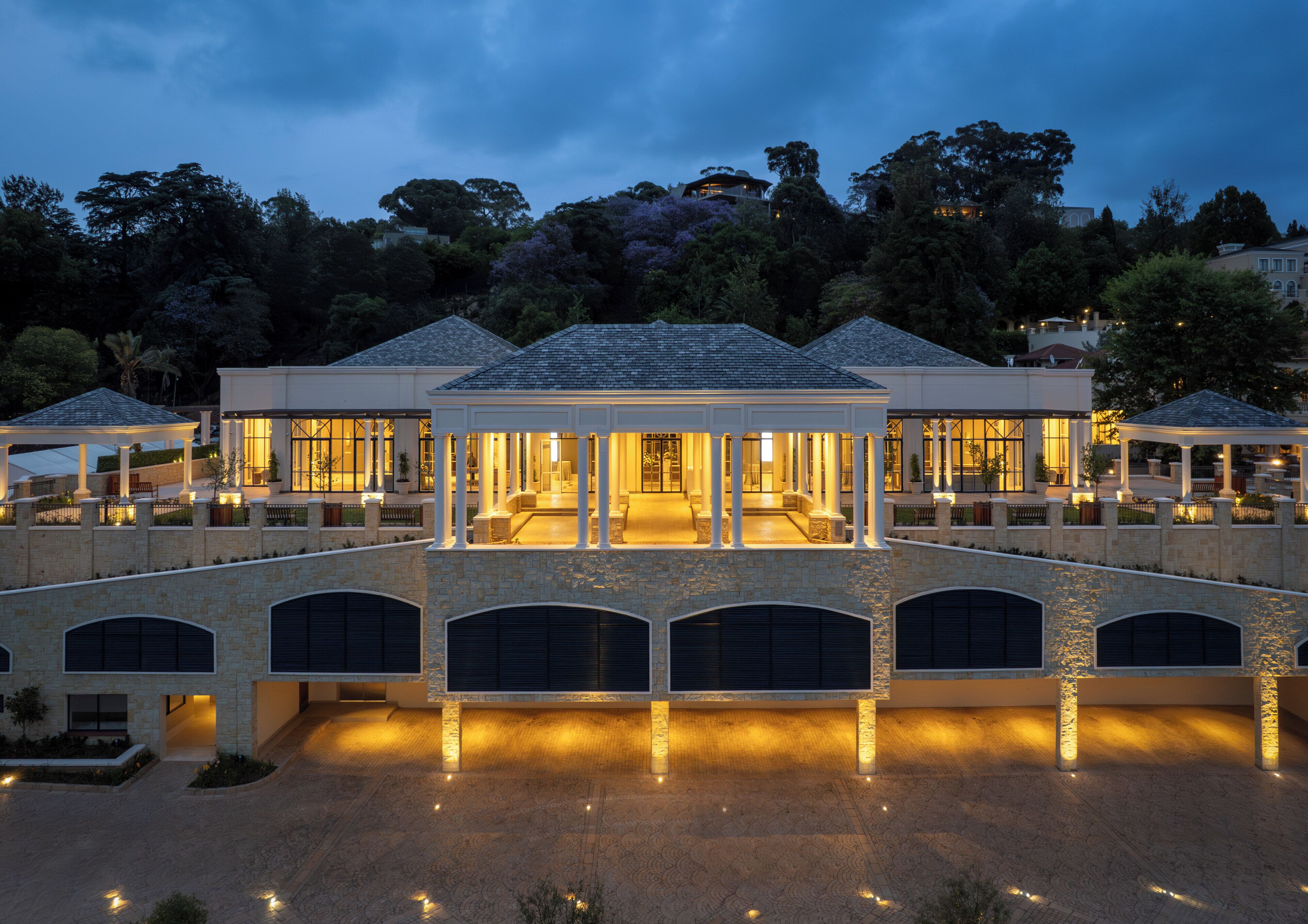 A large, multi-story building with a covered patio area, stone walls, and multiple garage doors.
