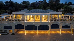 A large, multi-story building with a covered patio area, stone walls, and multiple garage doors.
