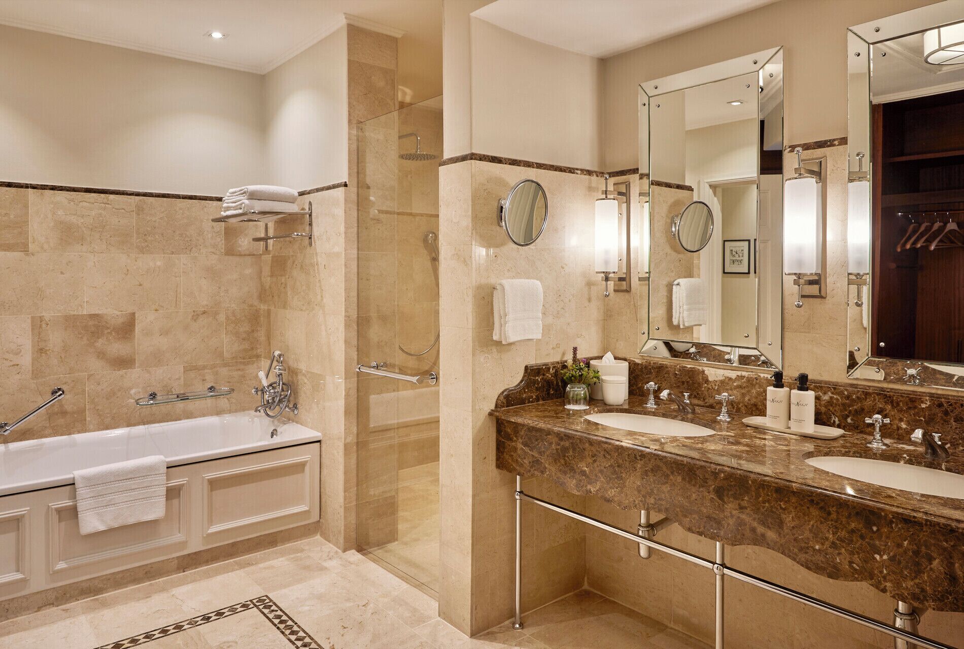 A modern bathroom with a bathtub, two sinks, a glass shower enclosure, and large mirrors.