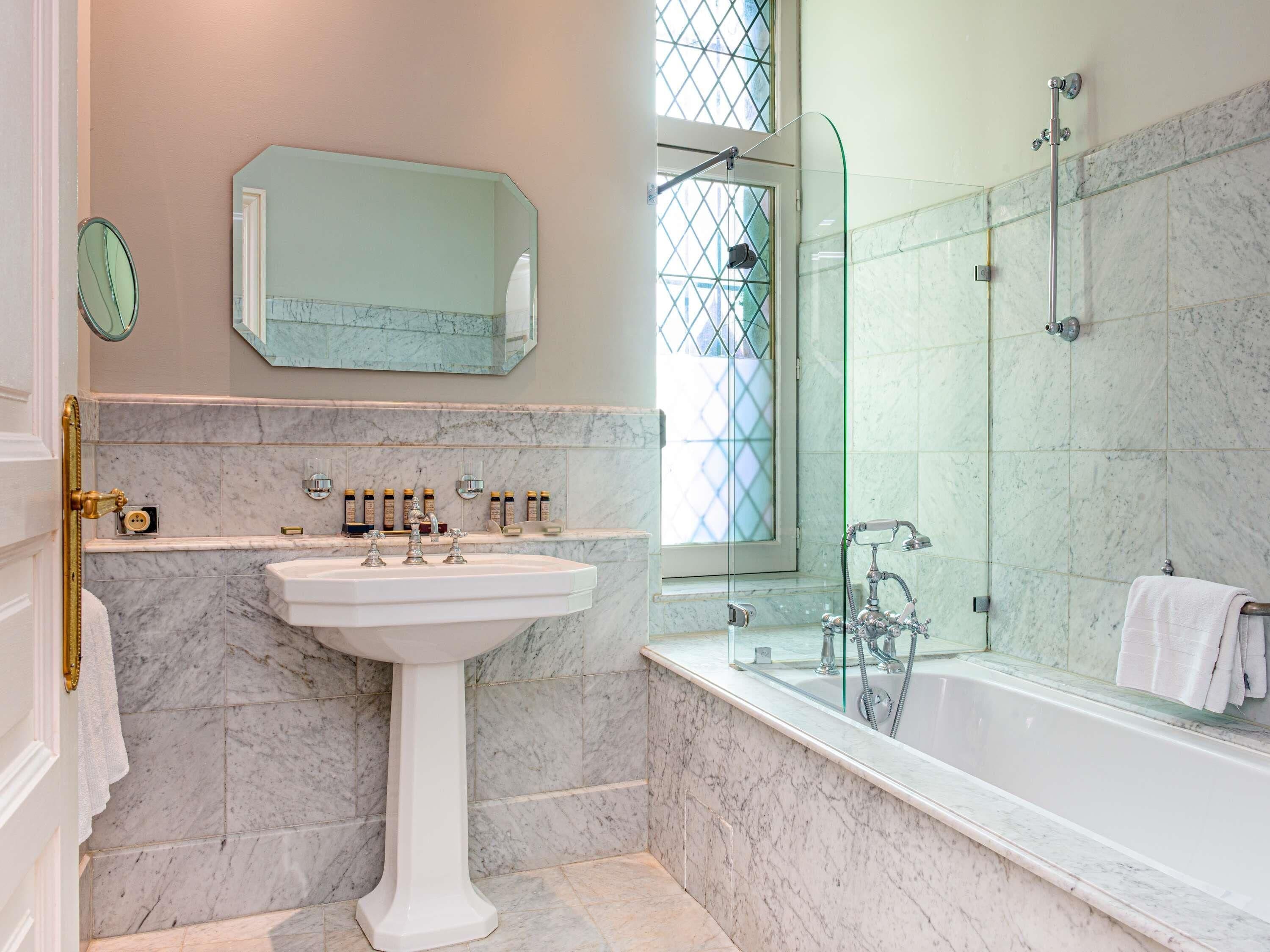 A bathroom with a pedestal sink, a bathtub, a shower, and a large mirror.