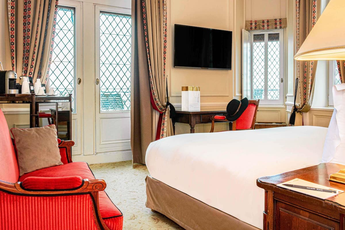 Habitación de hotel con una cama grande, un escritorio con una silla, un televisor y cortinas estampadas.
