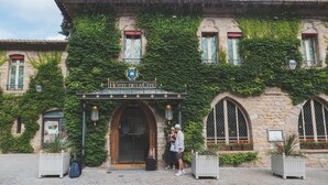 Un edificio histórico con fachada de piedra, ventanas en arco y un letrero que dice 'HOTEL DE LA CITE'.