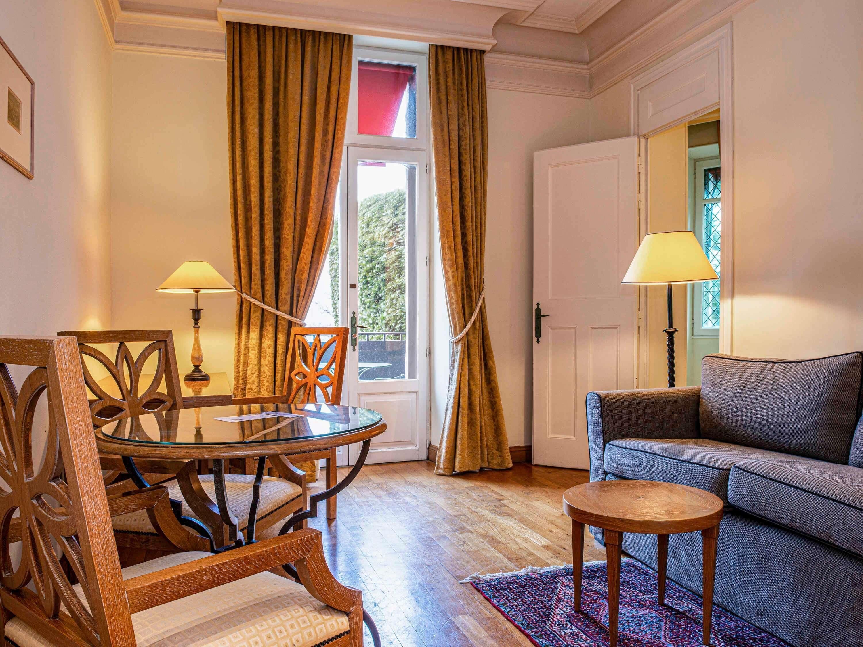 Une pièce comprenant une table ronde en verre, deux chaises, un canapé et deux lampes.