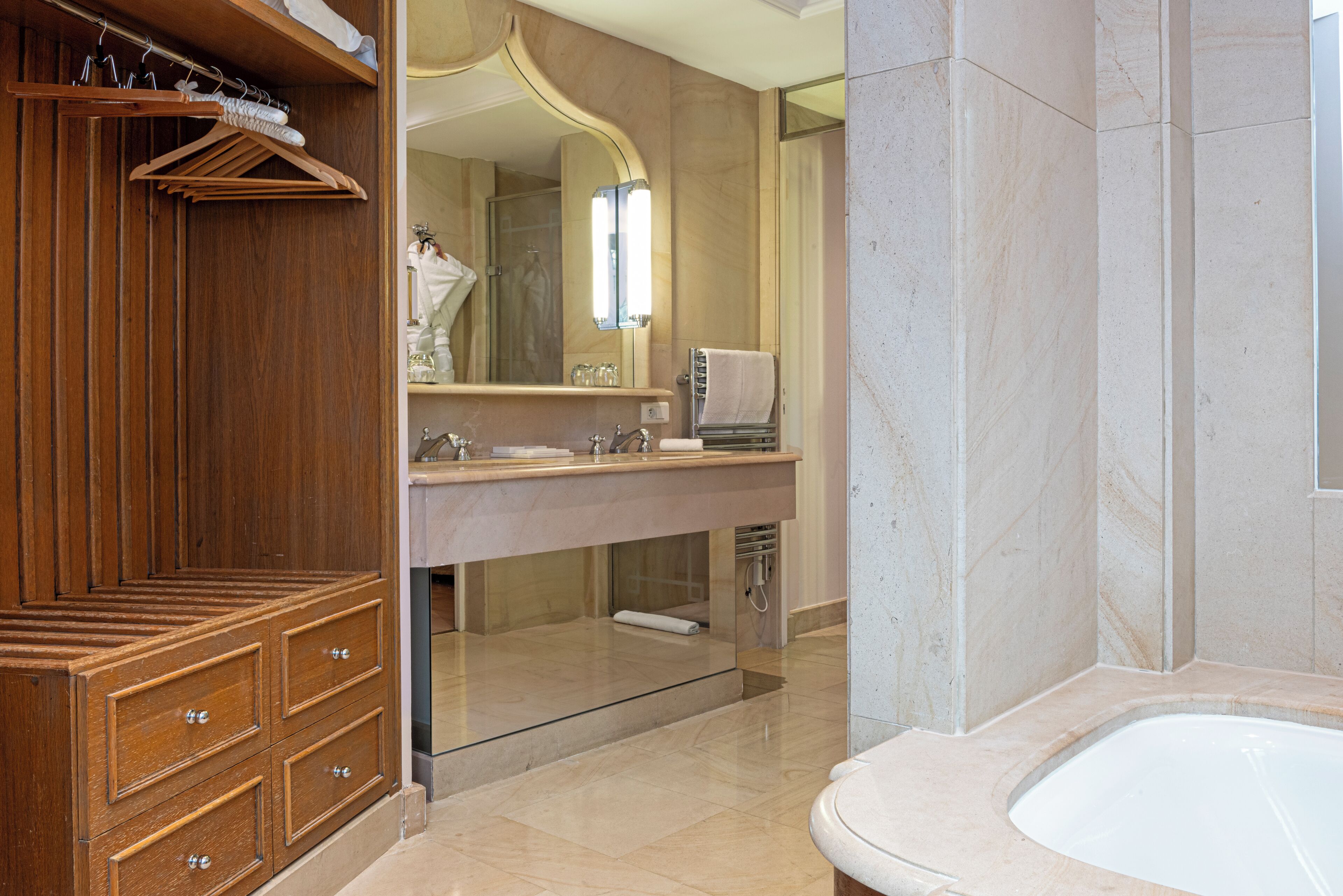 A modern bathroom with a wooden vanity, a large mirror, a bathtub, and a glass shower enclosure.