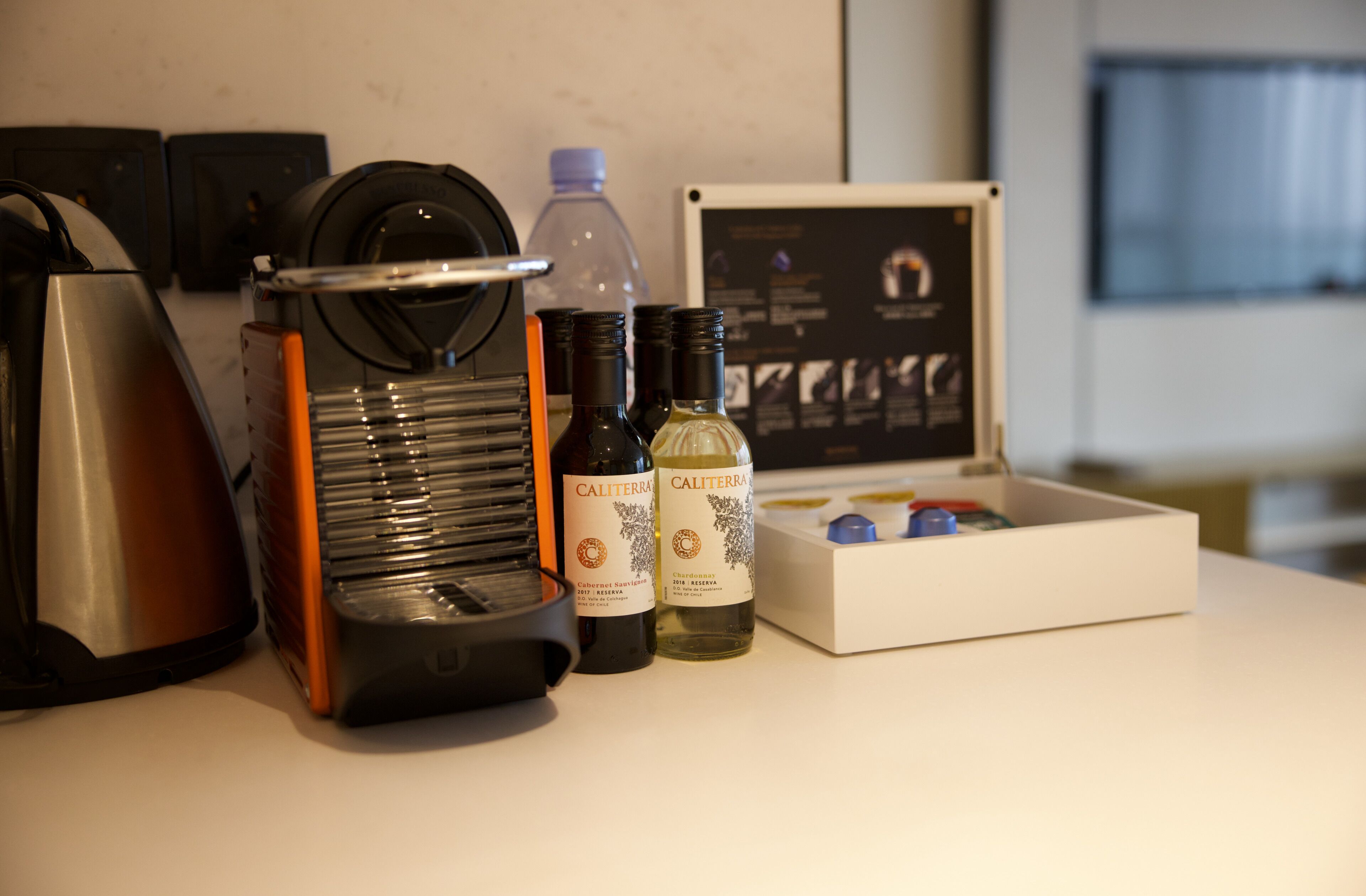 Eine Kaffeemaschine, zwei Flaschen Calitierra Wein und eine Kiste mit einer Weinflasche.