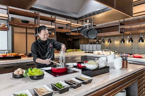 Chef prepares noodles in a well-equipped kitchen with modern design and ample counter space.