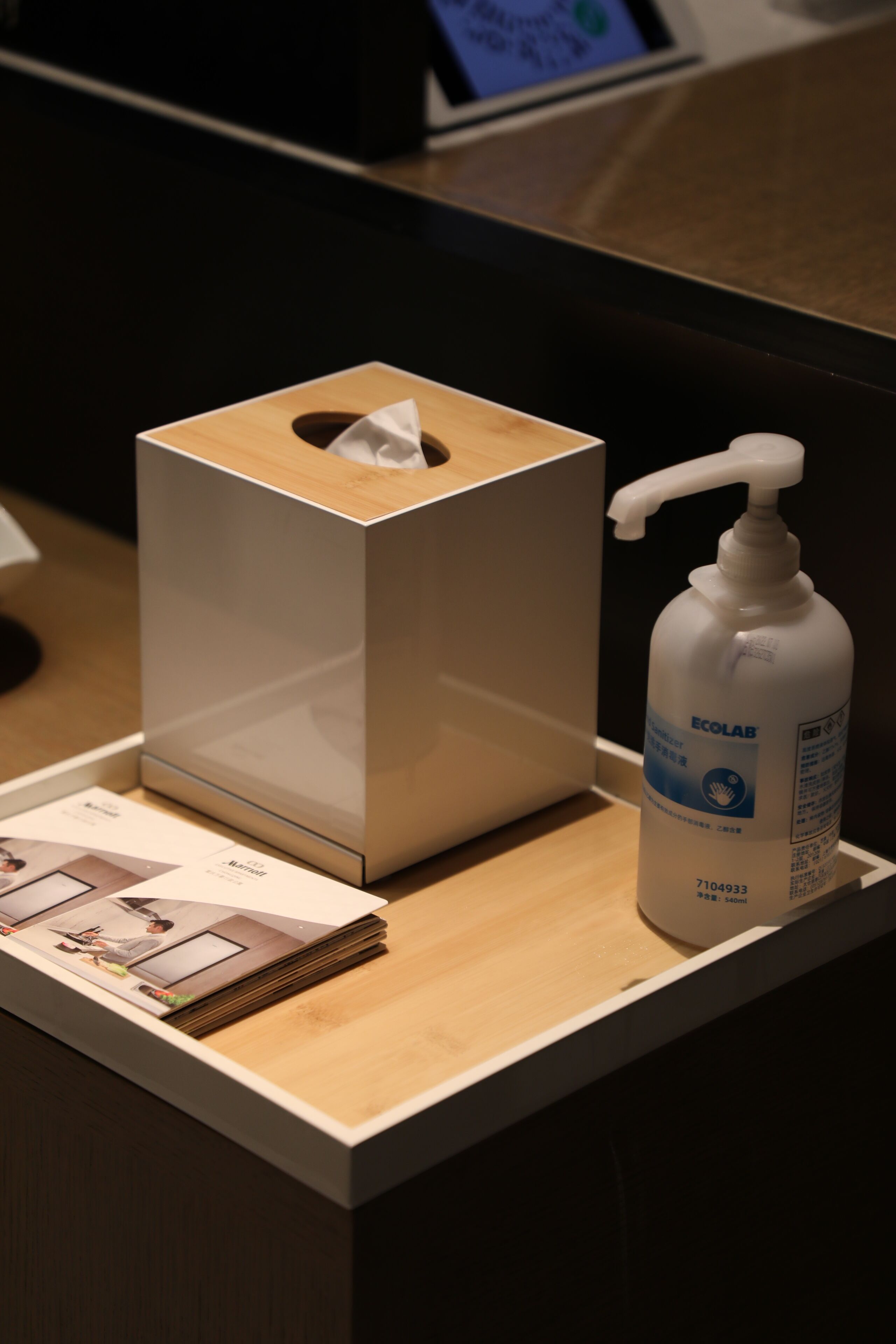 Un comptoir en bois avec une boîte de mouchoirs et une bouteille de gel hydroalcoolique.