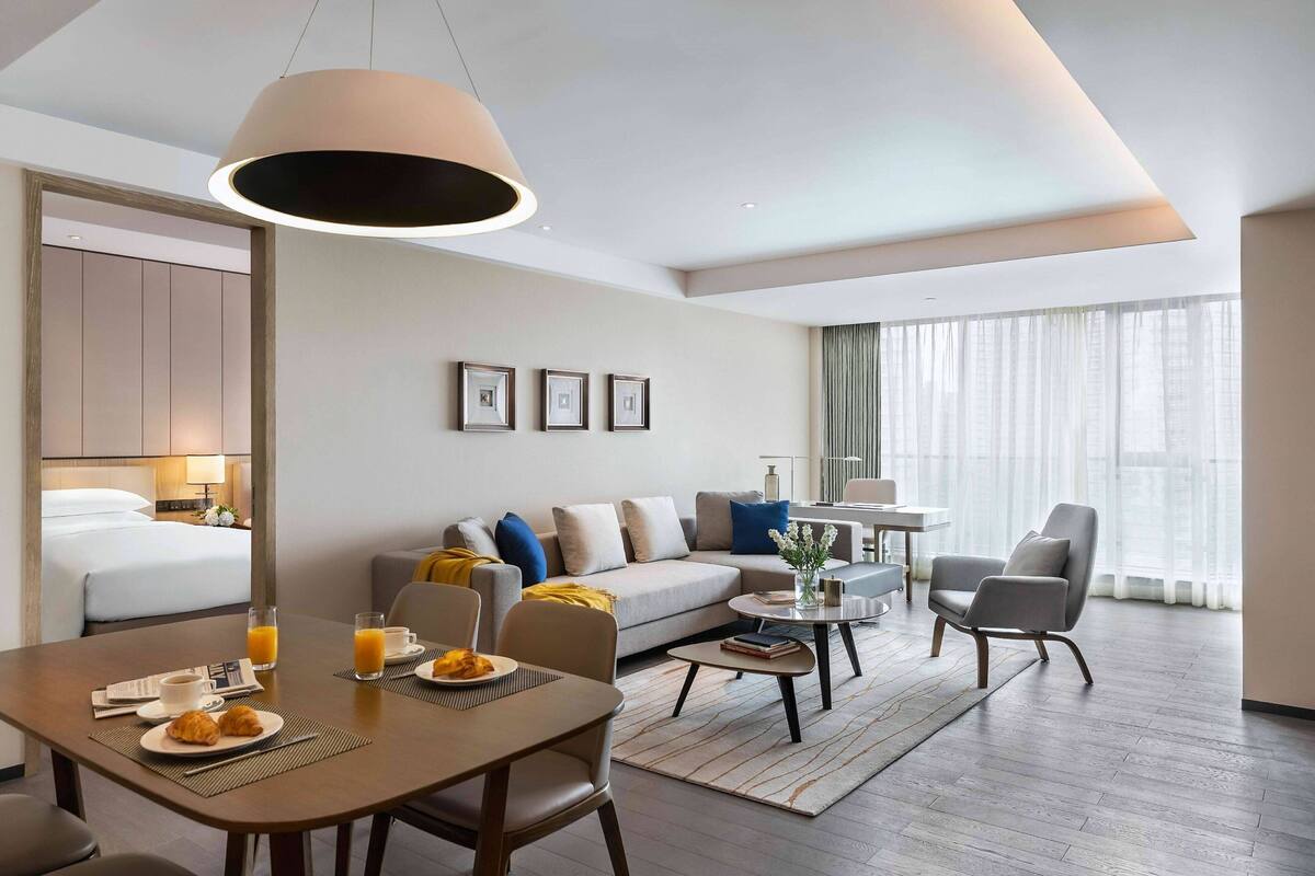 Ein modernes Hotelzimmer mit Essbereich, einer Couch, einem Couchtisch und einem Bett.