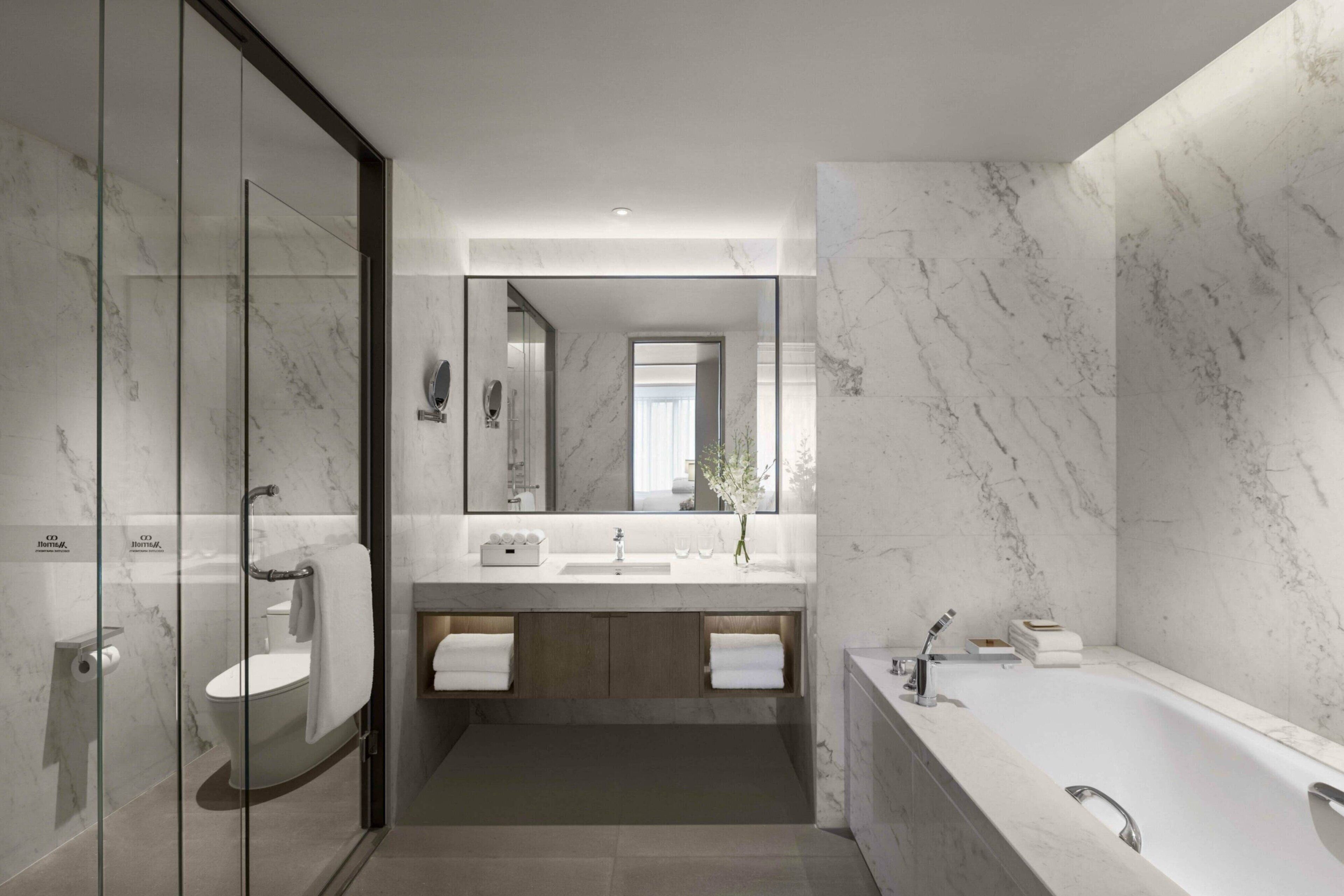 Une salle de bain moderne dotée d’une douche à parois de verre, d’une baignoire sur pieds et d’un meuble-lavabo avec un plan de travail en marbre.