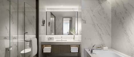 A modern bathroom with a glass shower enclosure, a freestanding bathtub, and a vanity with a marble countertop.