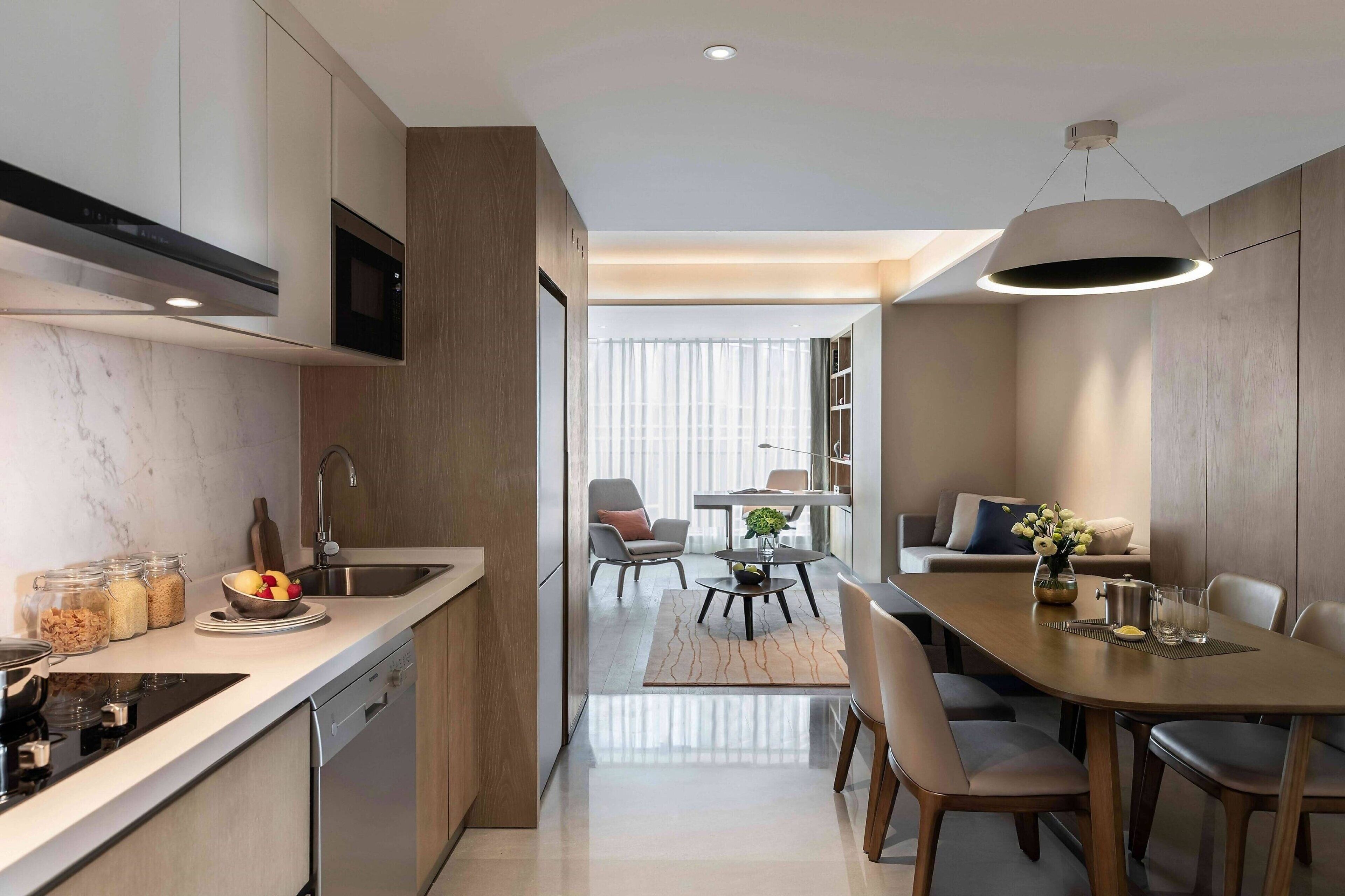 A modern kitchen with a built-in microwave, a dishwasher, and a dining area with a table and chairs.