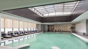 Piscina interior com espreguiçadeiras e claraboia.