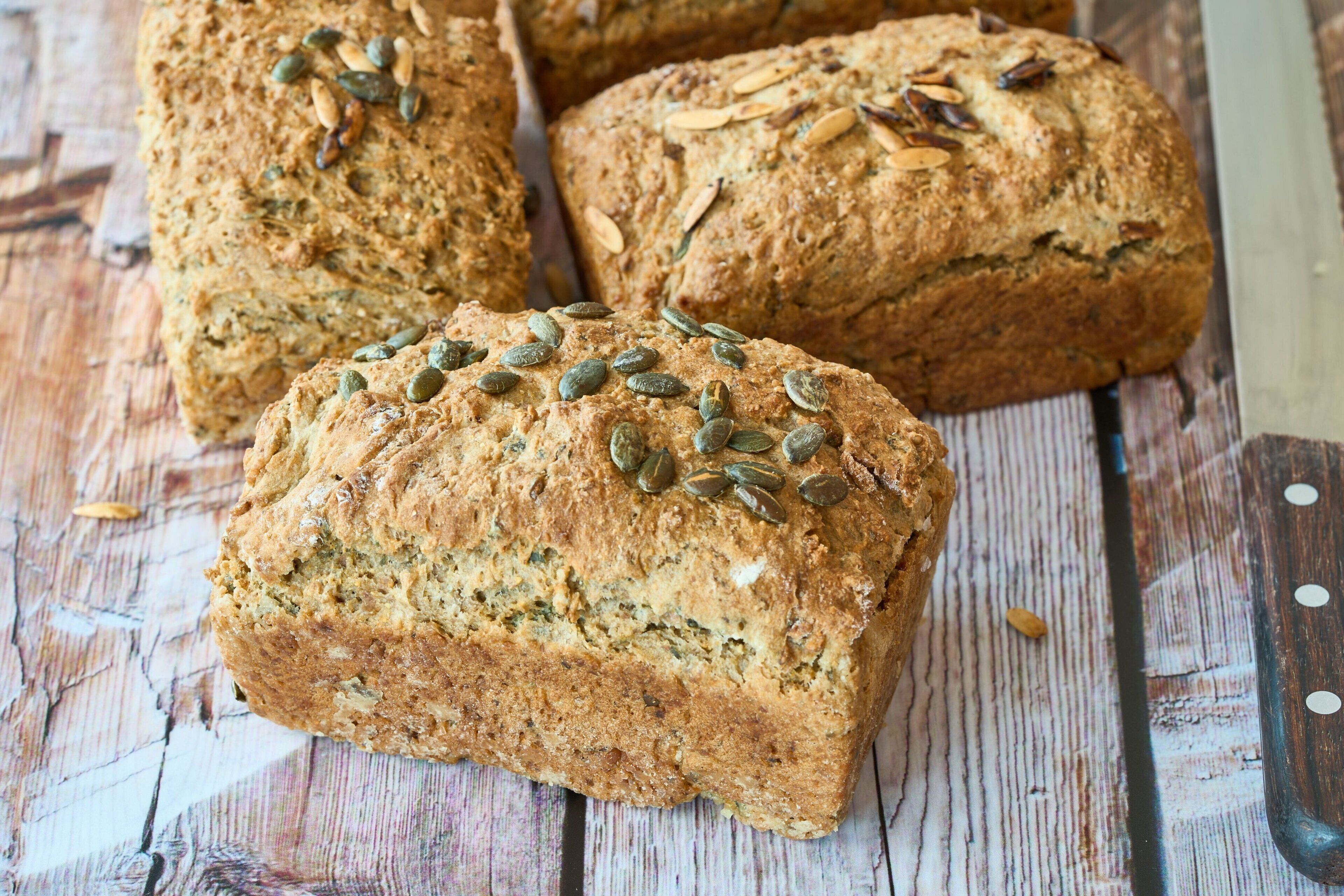 A loaf of bread with seeds on a wooden surface.