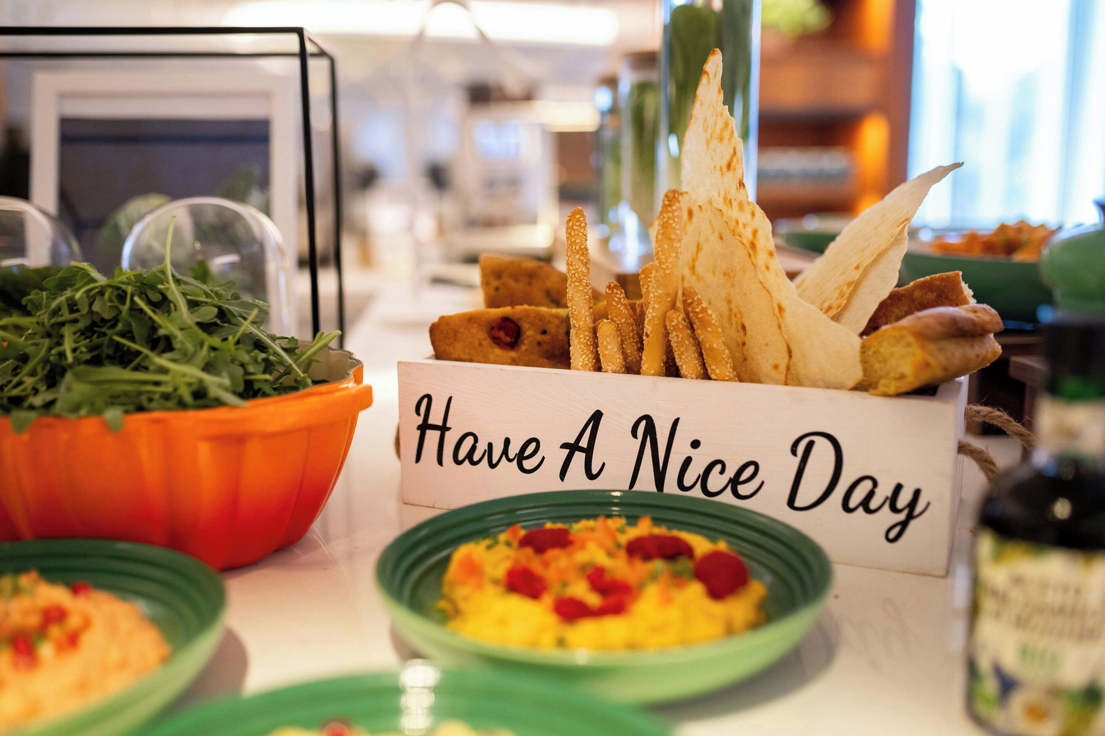 En buffetbord med forskellige retter og et skilt der står 'Have A Nice Day'.