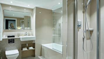 A modern bathroom with a glass-enclosed shower, a white bathtub, and a granite countertop sink.