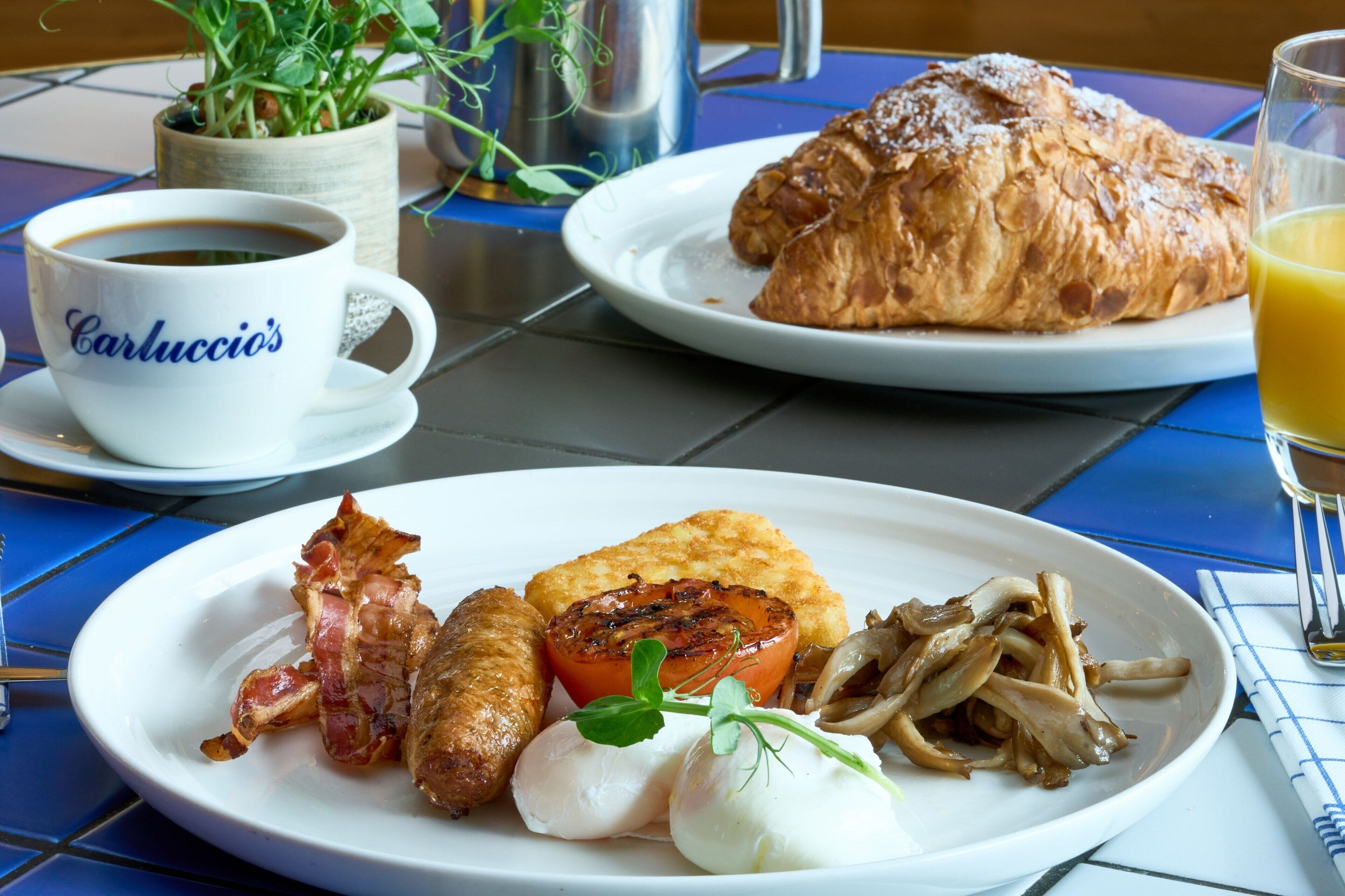 A breakfast setting with a plate of food, a cup of coffee, and a glass of orange juice.