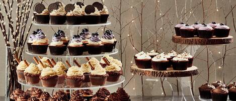 A multi-tiered display of various cupcakes and pastries, arranged on clear stands.
