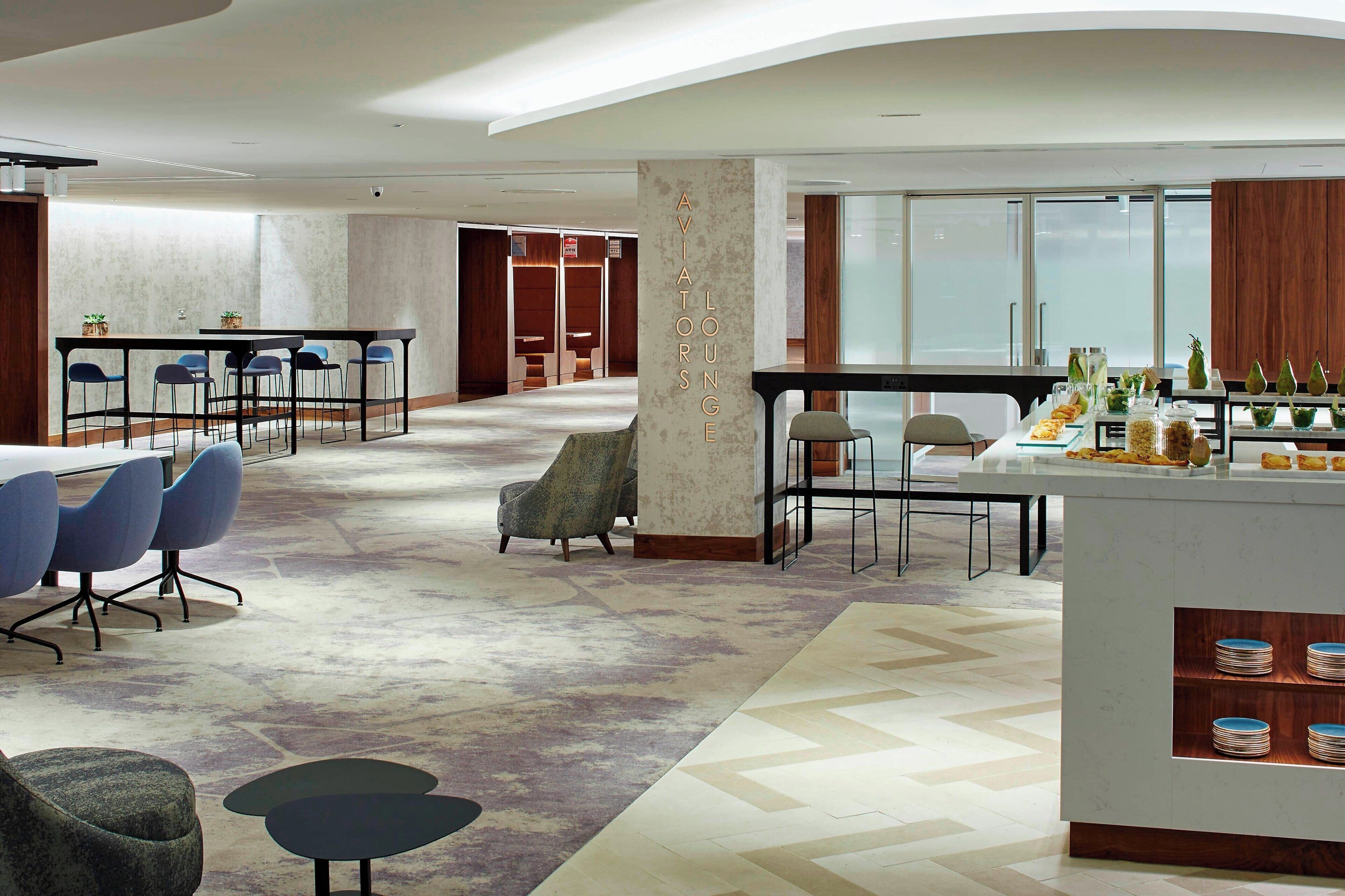 Un espace de détente moderne comprenant un bar, des coins salon et un buffet.