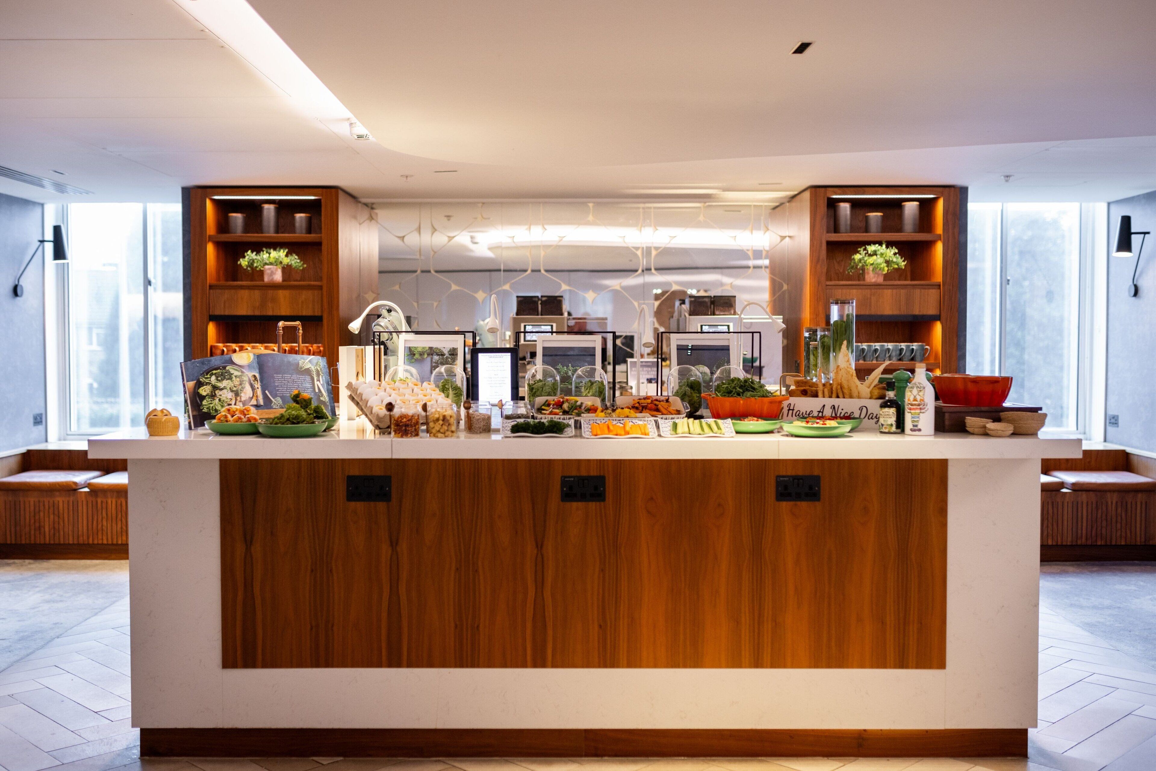 Une cuisine moderne dotée d’un îlot central, de meubles en bois et de divers produits alimentaires exposés sur le plan de travail.