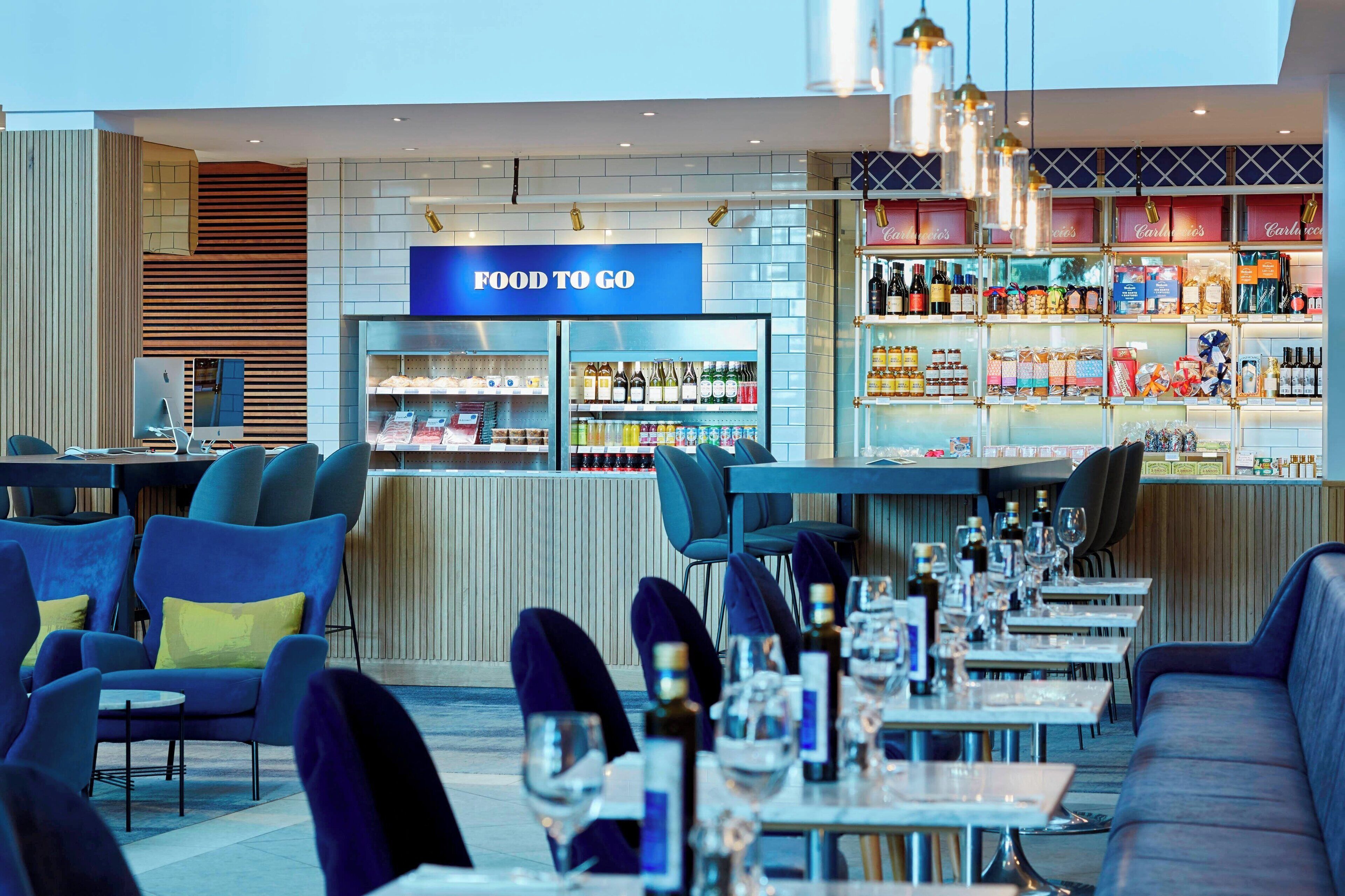 A restaurant with a 'FOOD TO GO' sign, seating arrangements, and a bar area with various beverages.