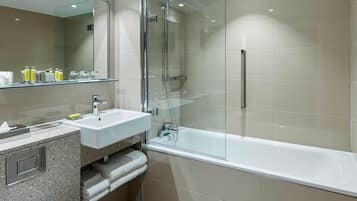 A modern bathroom with a glass-enclosed shower, a white sink, and a large mirror.
