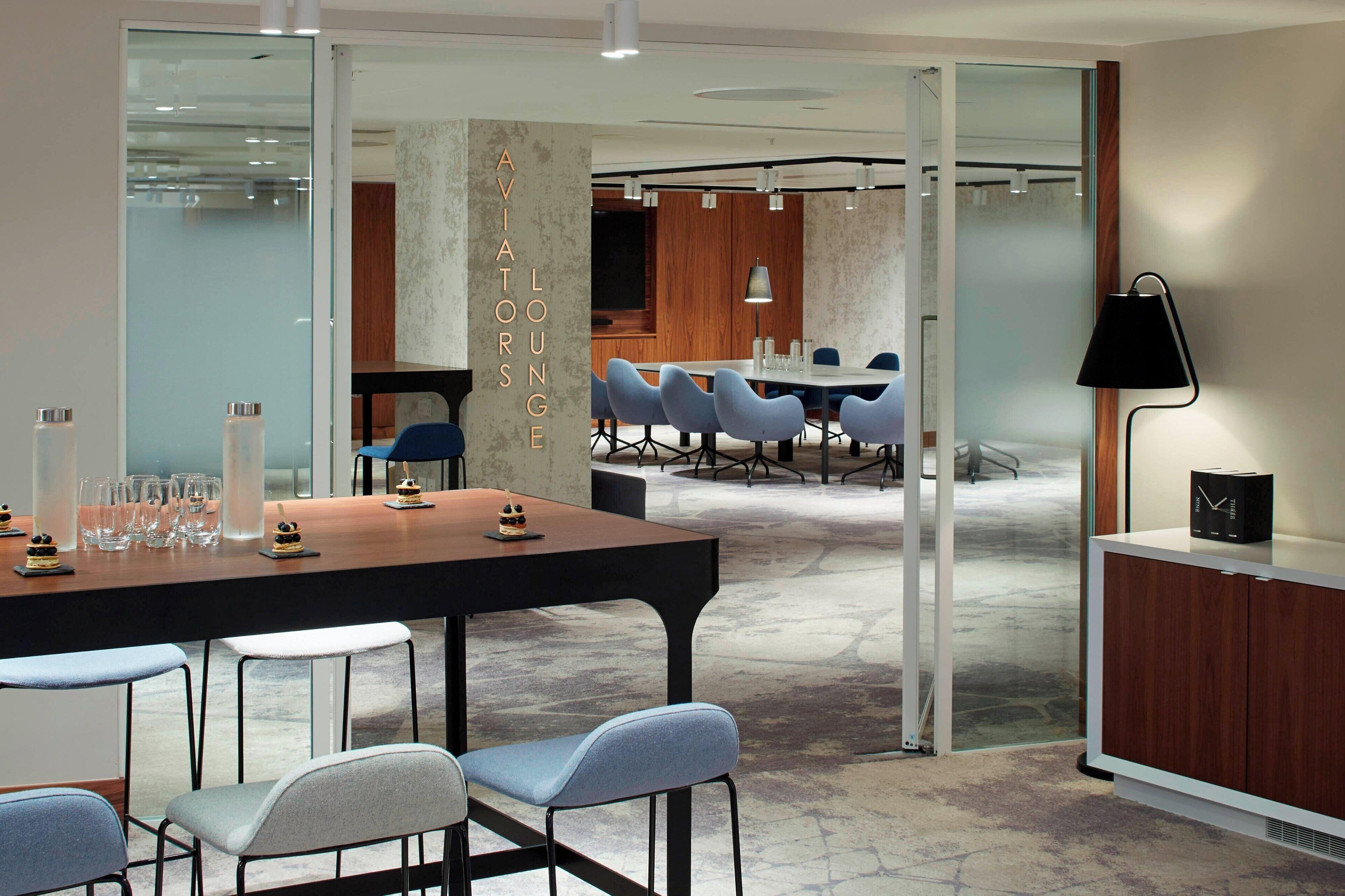 A modern conference room with a long table, blue chairs, and a wooden cabinet.
