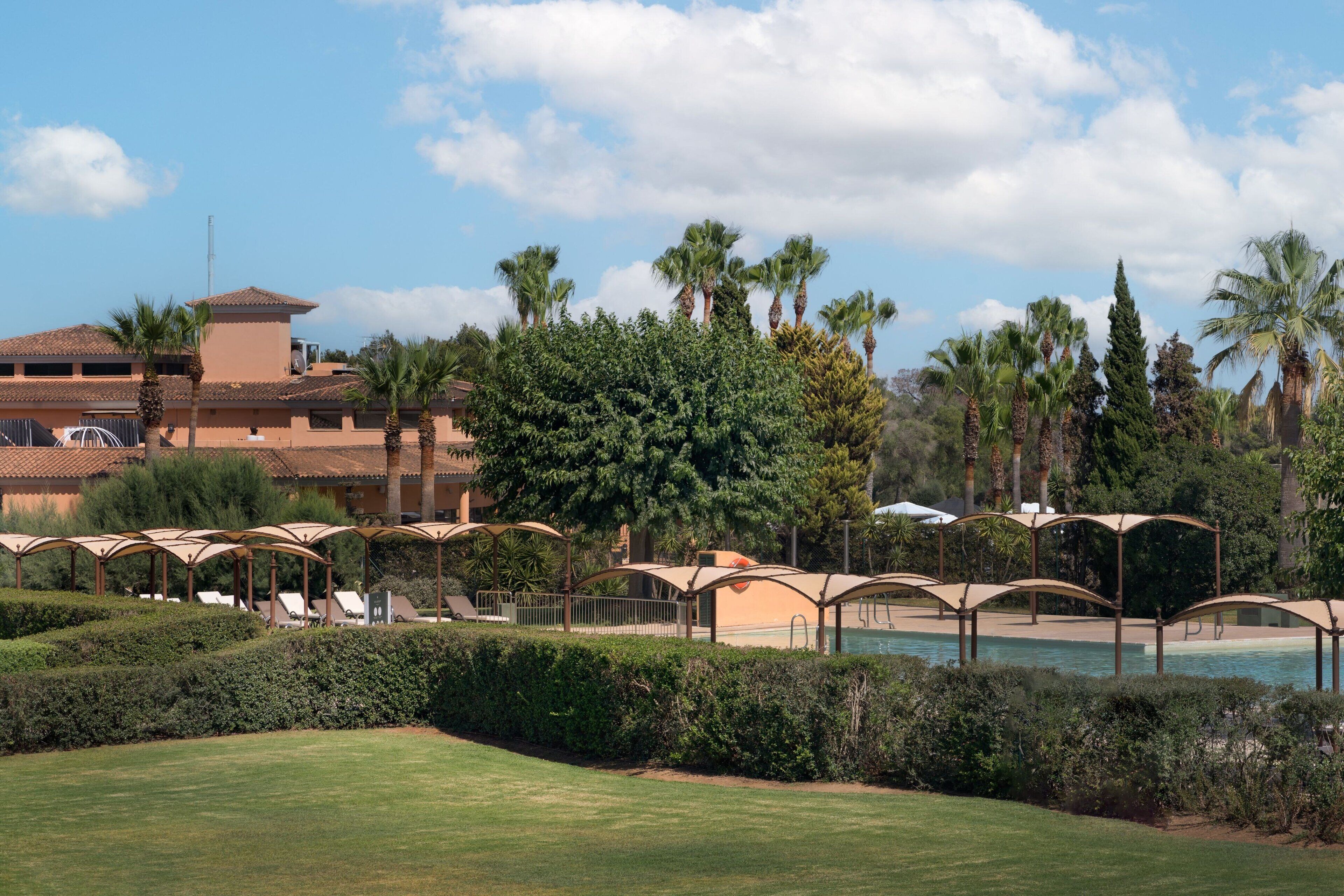 A resort with a pool, palm trees, and lounge chairs.