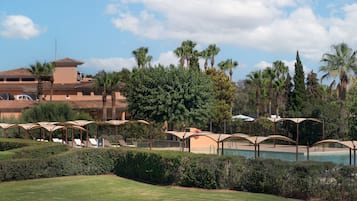 A resort with a pool, palm trees, and lounge chairs.