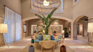 A spacious lobby with a high ceiling, a central seating area with wicker furniture, and a large plant. - Hacienda Son Antem Golf Resort, Autograph Collection (Llucmajor)