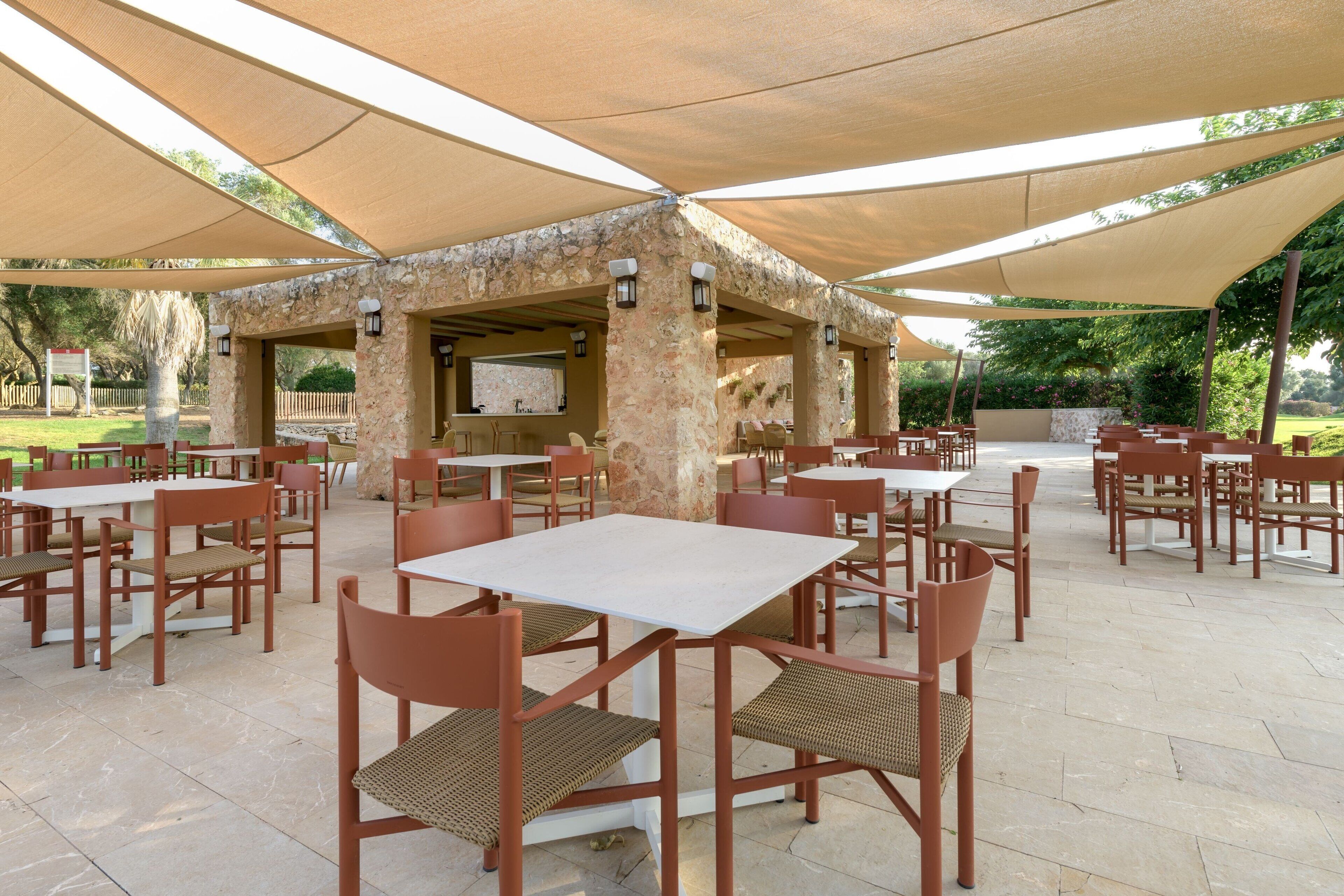 An outdoor patio area with stone pillars, tables, and chairs.
