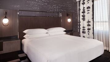 Ein Hotelzimmer mit einem großen Bett, zwei Nachttischen, einem Kopfteil mit einer Leuchte und einer Wand mit mathematischen Gleichungen.