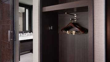 A modern bathroom with a dark wood vanity, a mirror, and a hanging coat rack.