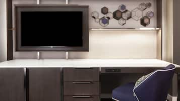 A modern office desk with a flat-screen TV, a built-in bookshelf, and a chair.