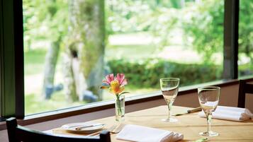 A dining table set with a vase of flowers, two wine glasses, and cutlery.